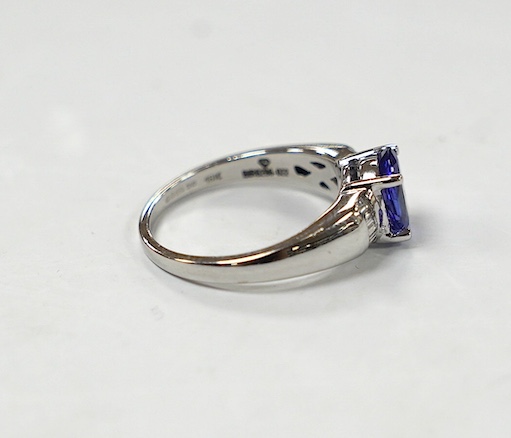 A modern 18ct gold and single stone oval cut tanzanite set ring, with baguette cut diamond cluster set shoulders, with accompanying AnchorCert report, stating the stone to weigh 1.20ct, size L, gross weight 4.1 grams. Co